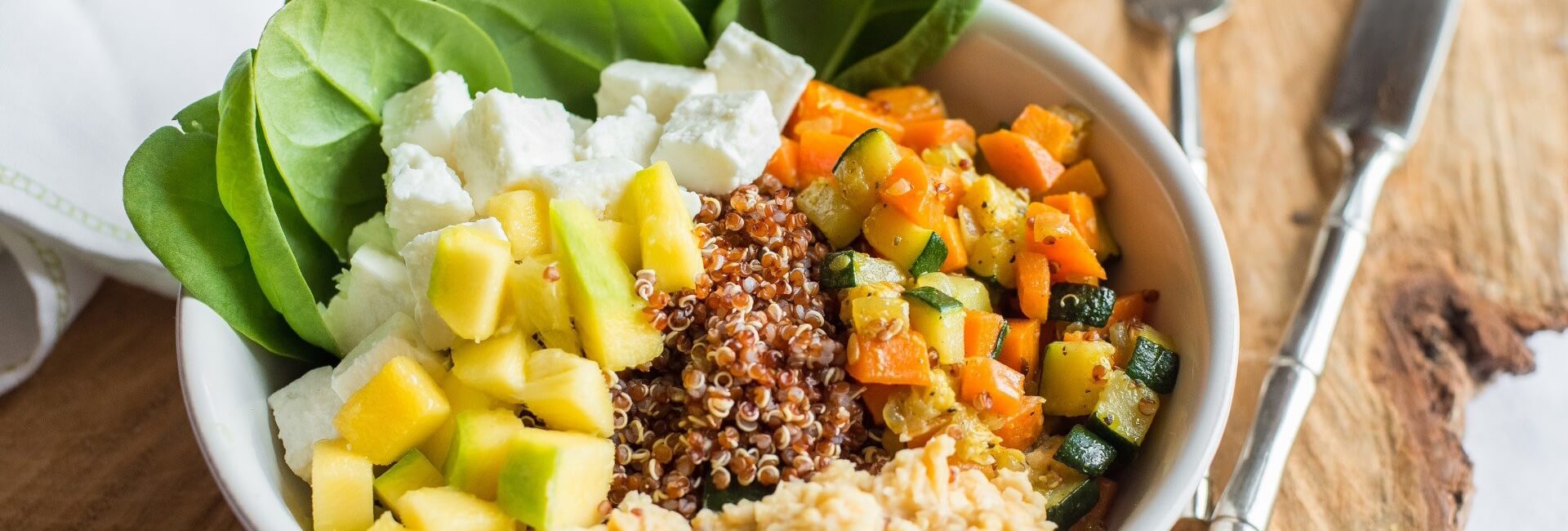Bowl de quinoa com cenoura e curgete salteadas, cubinhos de manga, húmus e queijo feta